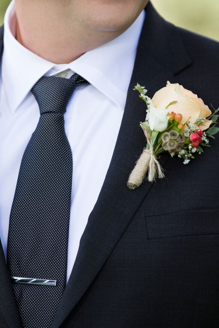 Casey wore a classic black suit with a black-and-white polka-dot tie. The wedding day's florist, Down The Aisle By Maria, created a boutonniere that followed the country-inspired color palette using a peach rose and red berries wrapped in twine.