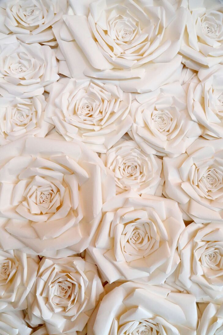 A whimsical paper flower wall with big garden roses served as a backdrop for the wedding cakes and created a focal point for the reception space.