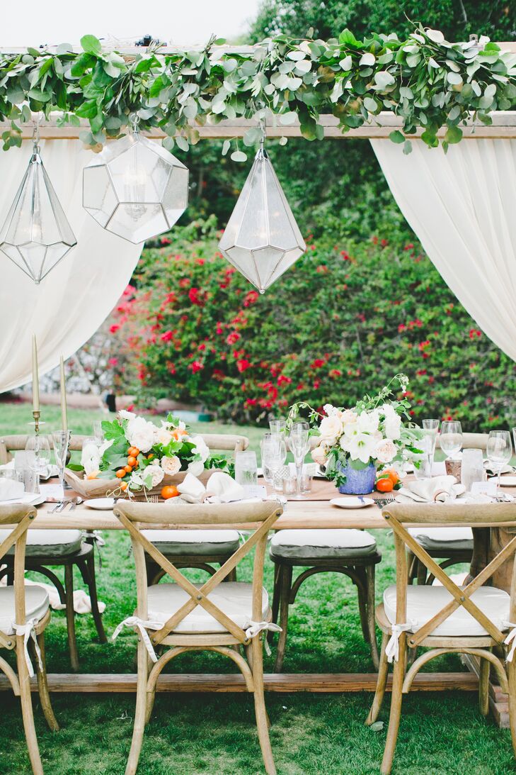 At the reception at Rancho Valencia in Rancho Santa Fe, California, chandeliers and lush eucalyptus garlands were hung from wooden rafters above the long banquet tables.