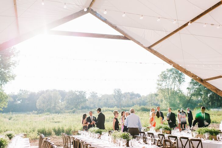 The bride's father built a smaller tent attached to the main tent for guests to enjoy a casual cocktail hour on the property, where they were able to walk down to the pond of sit along benches lining the space,