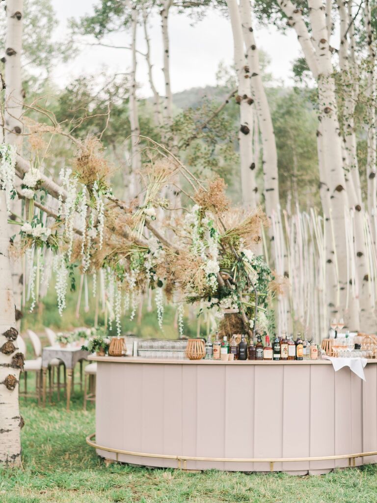 Round wooden outdoor bar space surrounded by beech trees.
