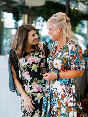 Ladies in Elegant Floral Dresses Embracing at Italian-Themed Rehearsal Dinner