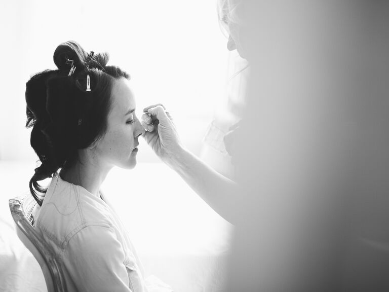 Bride getting makeup done before wedding 