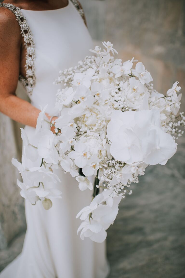 Cascading white wedding bouquet with orchids and baby's breath