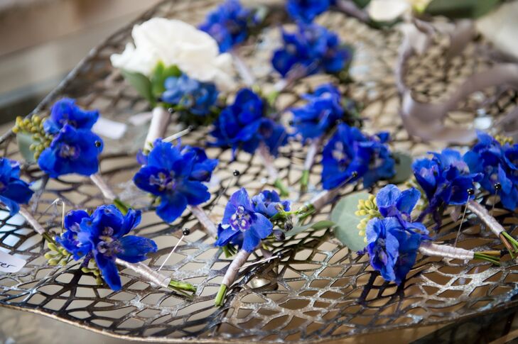The groomsmen wore blue delphinium boutonnieres with greenery accents to match the bold color palette and the bridesmaid dresses.