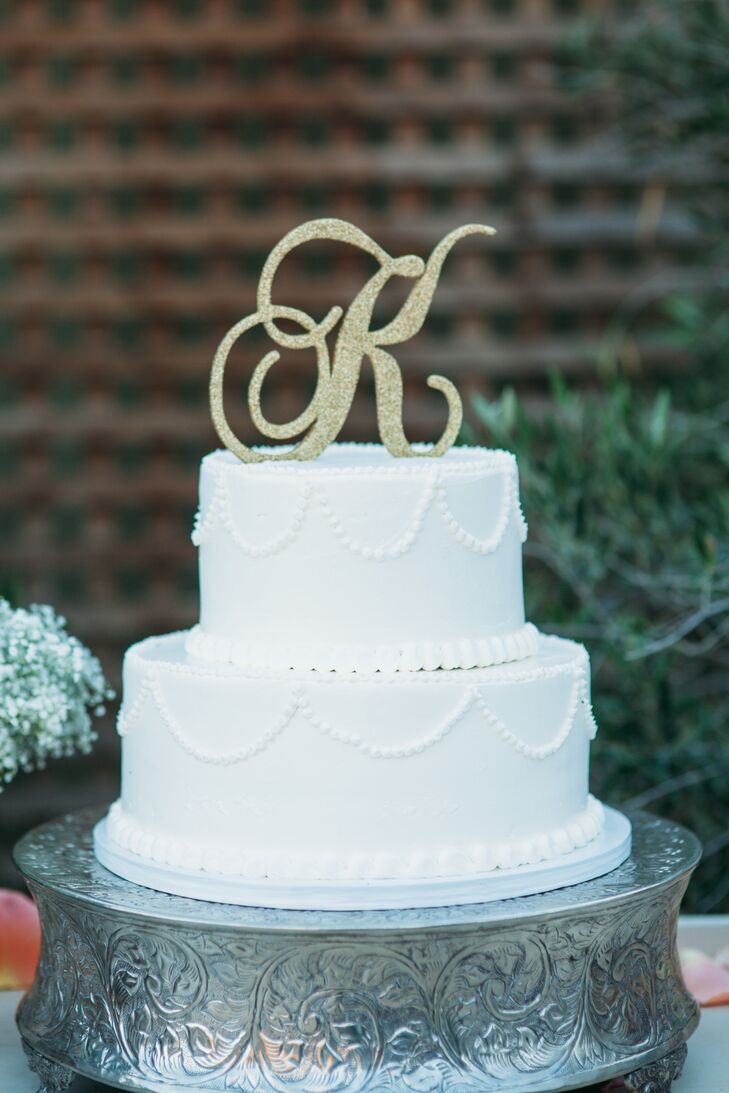 The traditional white wedding cake stood two tiers tall, with beaded icing around the bottom of each layer. The dessert had a gold topper of Monique and Shade's last-name initial, created by Solvang Bakery, which also made four other cakes served at the wedding.
