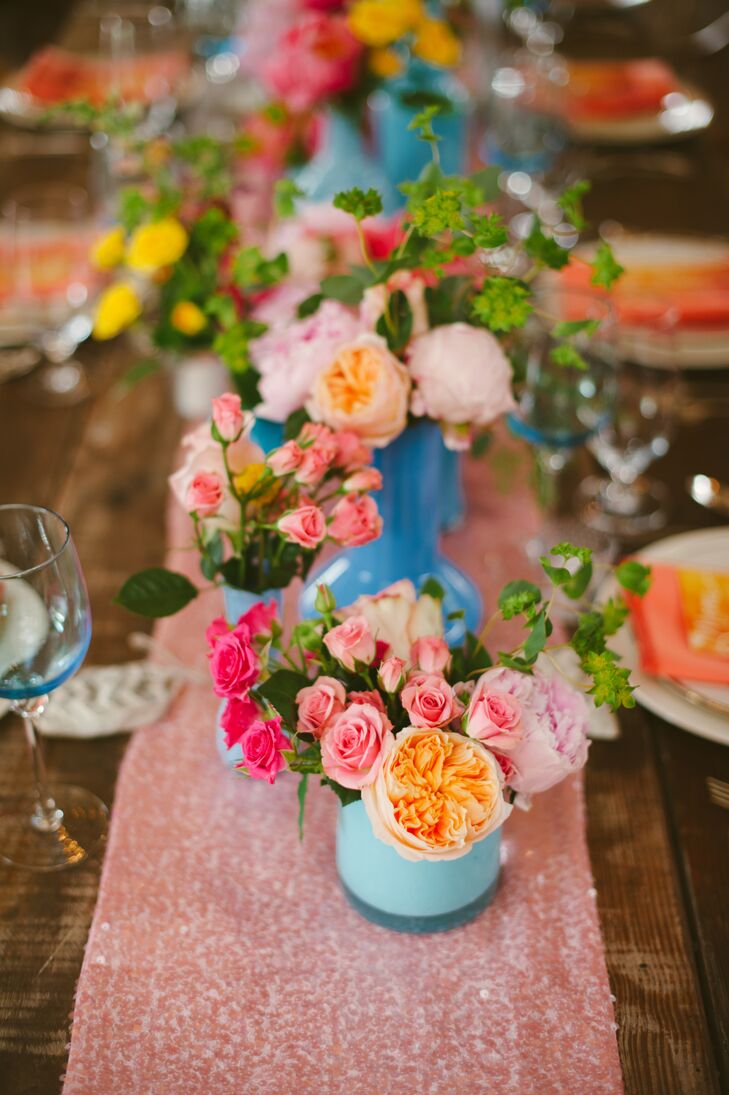 Petite flower arrangements filled with colorful blooms decorated the middle of the wooden dining table draped with pink runners, where guests sat for the barn reception.