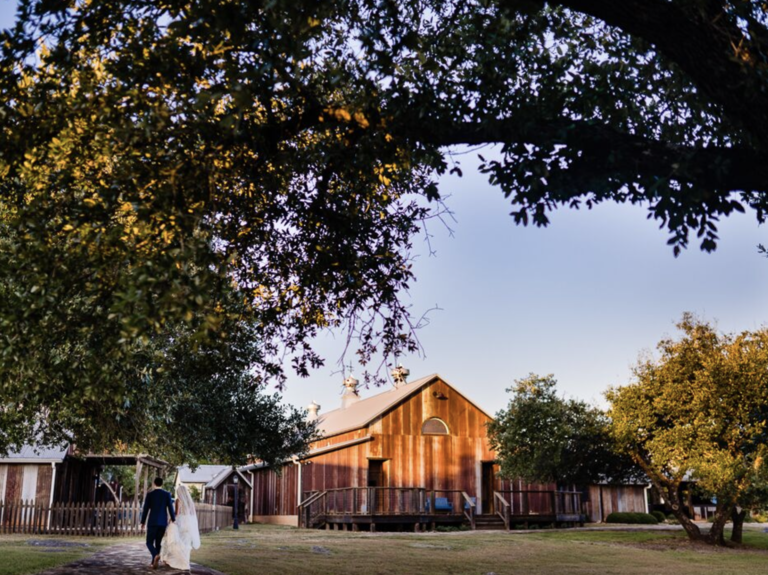 Bride and groom walking toward barn at Allegro Wedding & Events Venue in Dripping Springs, TX