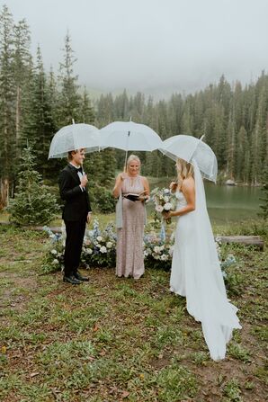 Groom, Bride and Officiant Holding Umbrellas at Rainy Mountain Ceremony With Floral Altar, Lakeside