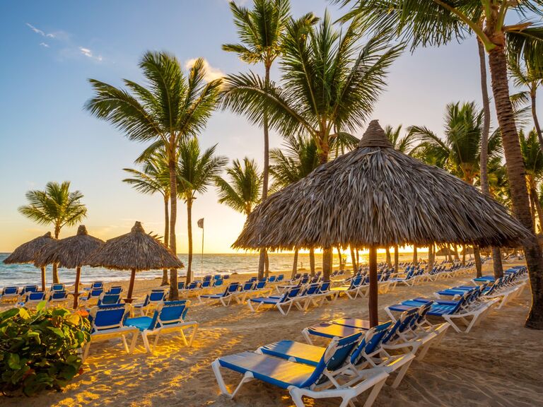 Beach view at a tropical resort in Punta Cana featuring lounge chairs, umbrellas, and palm trees.