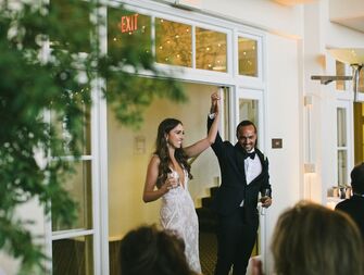The happy couple enter their wedding reception holding hands.