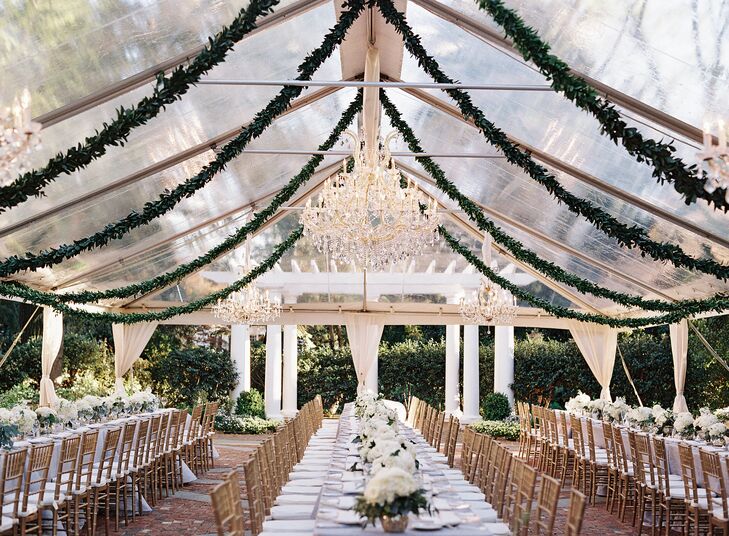 The garden party motif came to life with lush greenery. Garlands of greenery were hung from the cross poles at the top of the clear tent to give the covered reception space a natural feel.