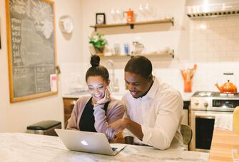 Engaged couple registering for gift cards on laptop at home