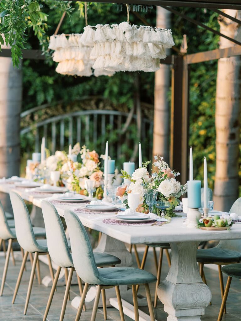 Beach reception tablescape with blue velvet chairs, blue candles and white cloth chandeliers
