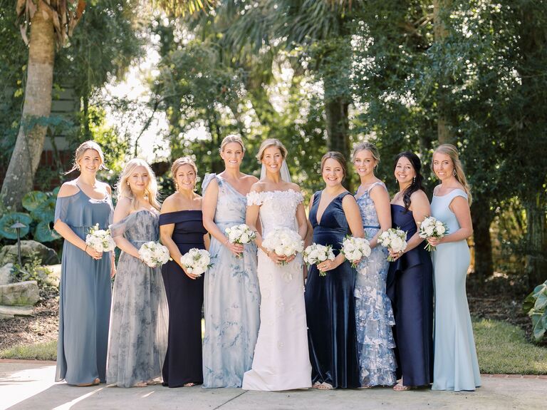 bride stands with bridesmaids wearing mix-and-match dresses in navy and light blue