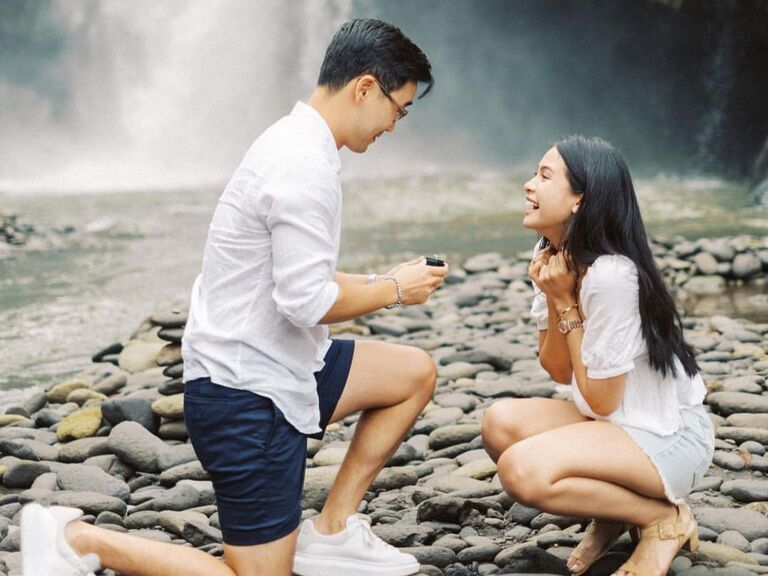 Couple getting engaged in front of a waterfall