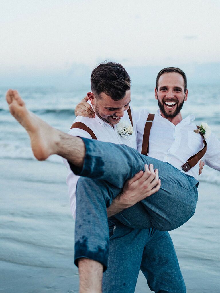 Groom laughing during summer wedding portraits on beach
