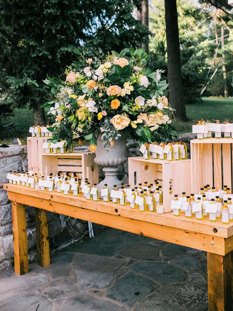rustic wedding favor display with crates on wooden table and miniature bottles of olive oil