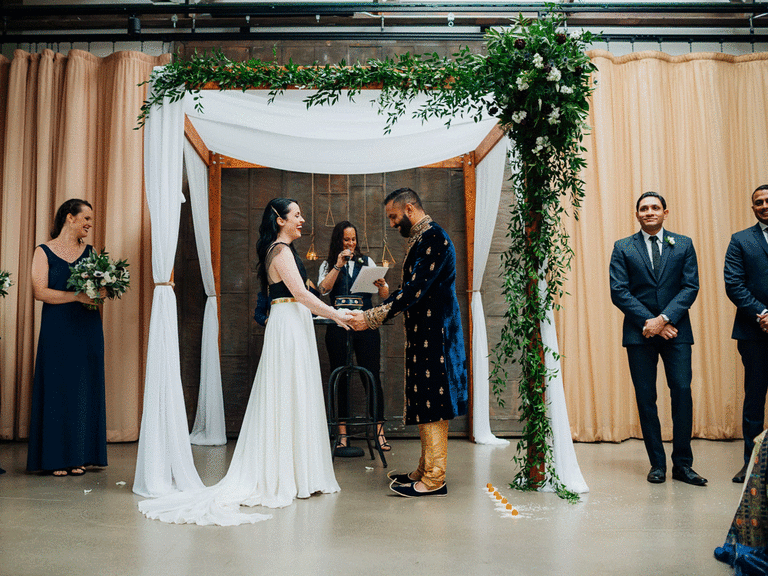 Bride and groom having an interfaith ceremony beneath a draped mandap.