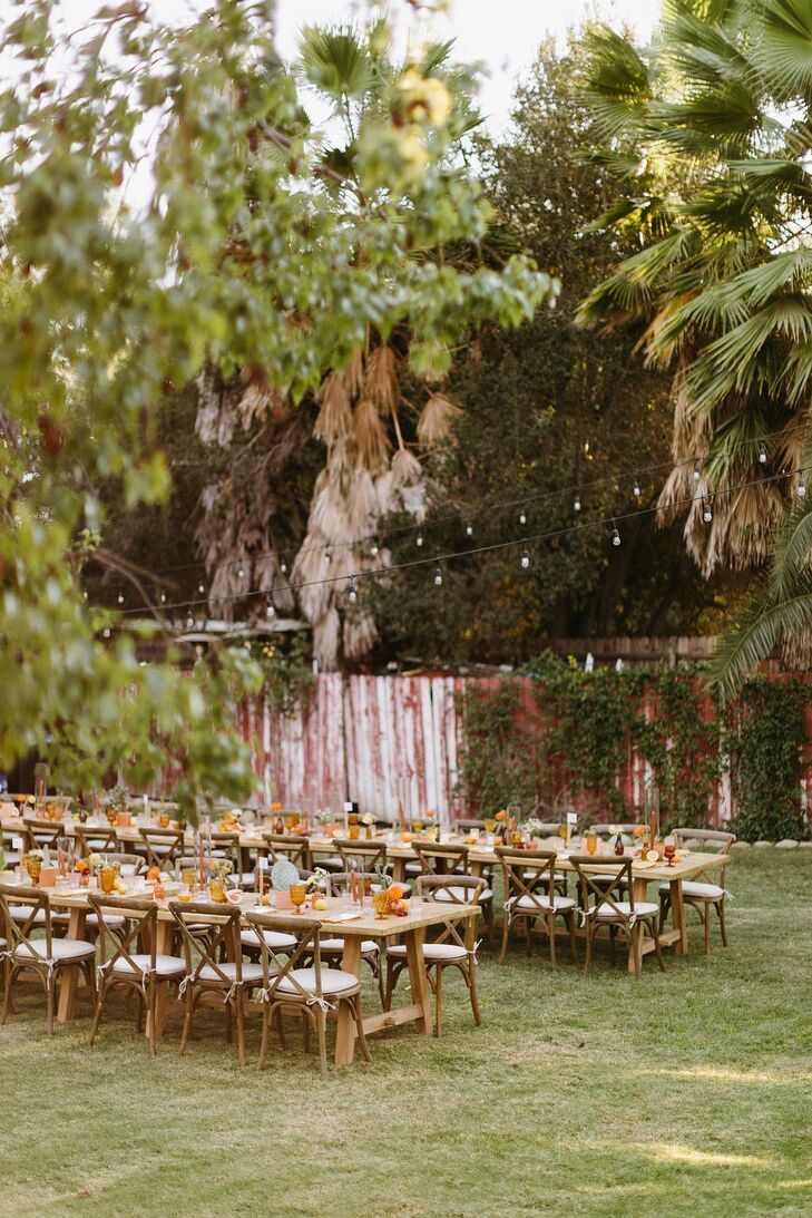 Long Dining Tables on Lawn of Motel Under String Lights With Burnt Orange Details