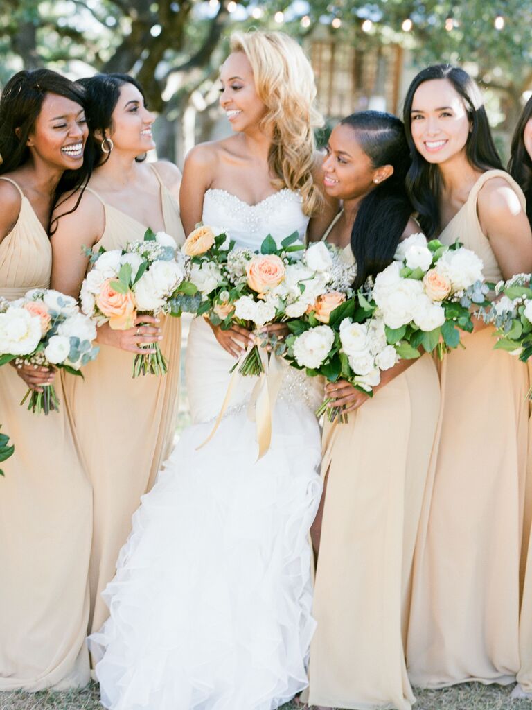 bride stands with bridesmaids holding white and yellow bouquets