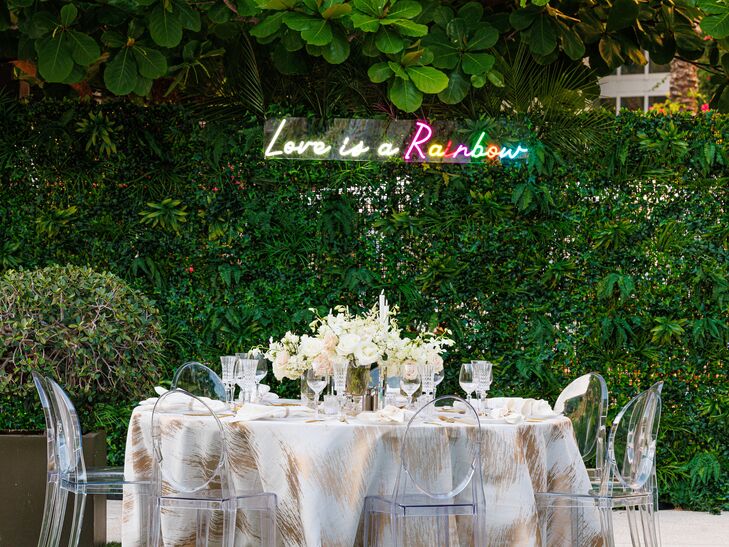 Round Table With Textured, White-and-Rose Hold Linen, Ghost Chairs Under Neon Sign