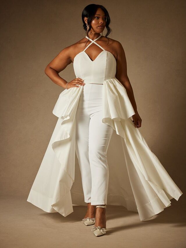 Model wears a white top with matching pants and an attached skirt. 