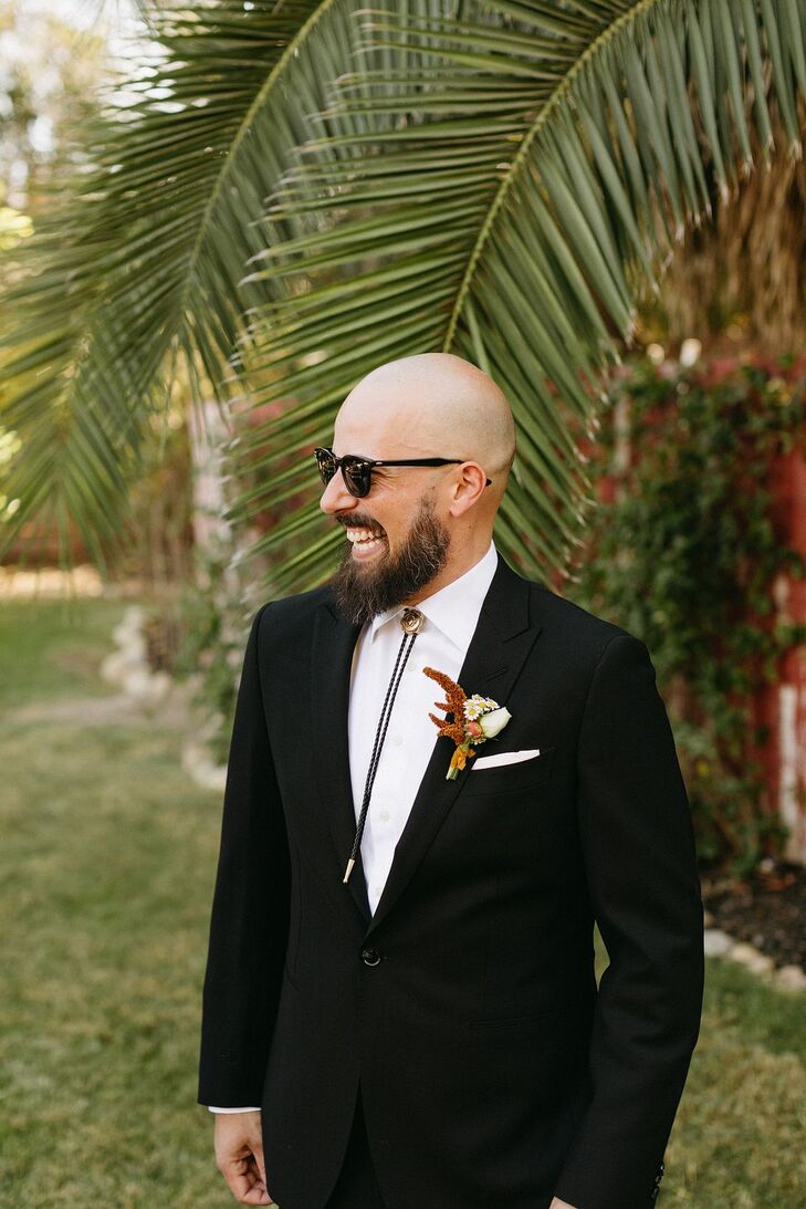 Groom in Black Suit With a Bolo Tie and a Bright Boutonniere Sporting a Bolo Tie