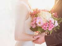 Bride holding a pink and white bridal bouquet, held in her father's hands