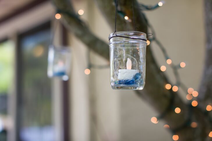 Aly made many of the decorations for the wedding day, including these glass mason jars filled with electronic candles that hung from the branches of a tree, wrapped in twinkling string lights.