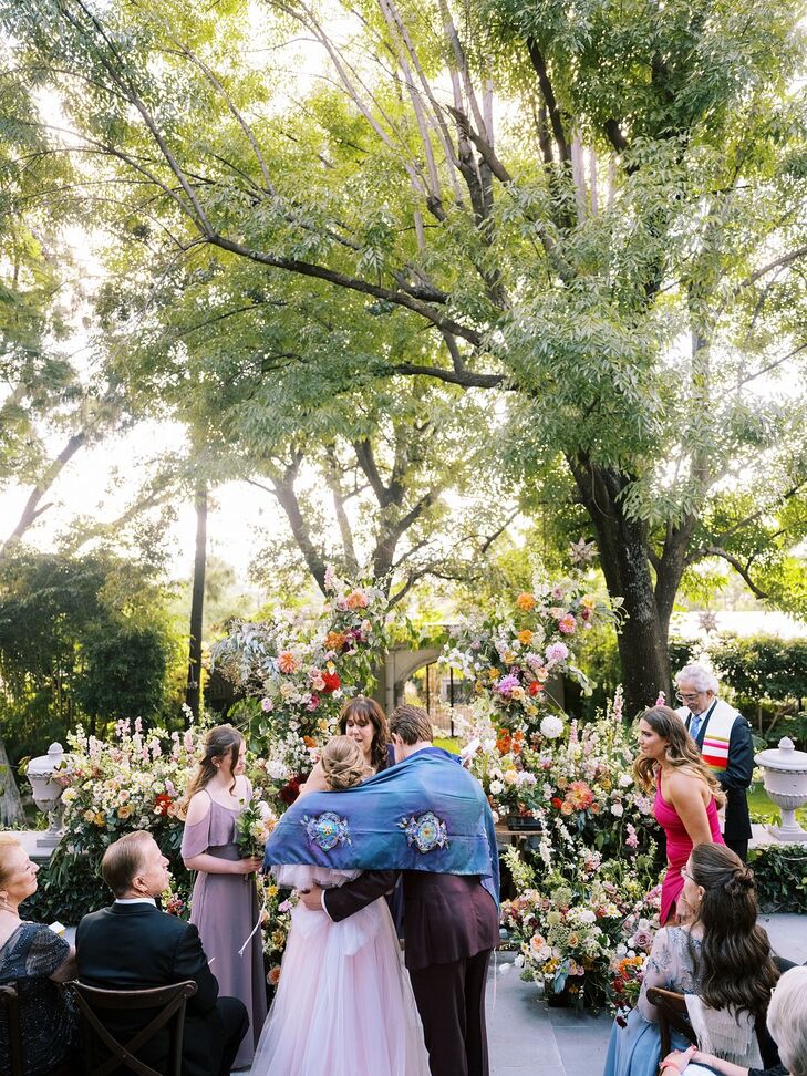 Christian Bride and Groom Being Blessed By Jewish Friend at Religious Ceremony, Lush Floral Altar