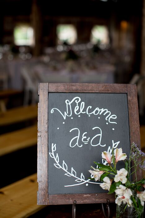 A chalkboard sign welcome guests into the reception barn.