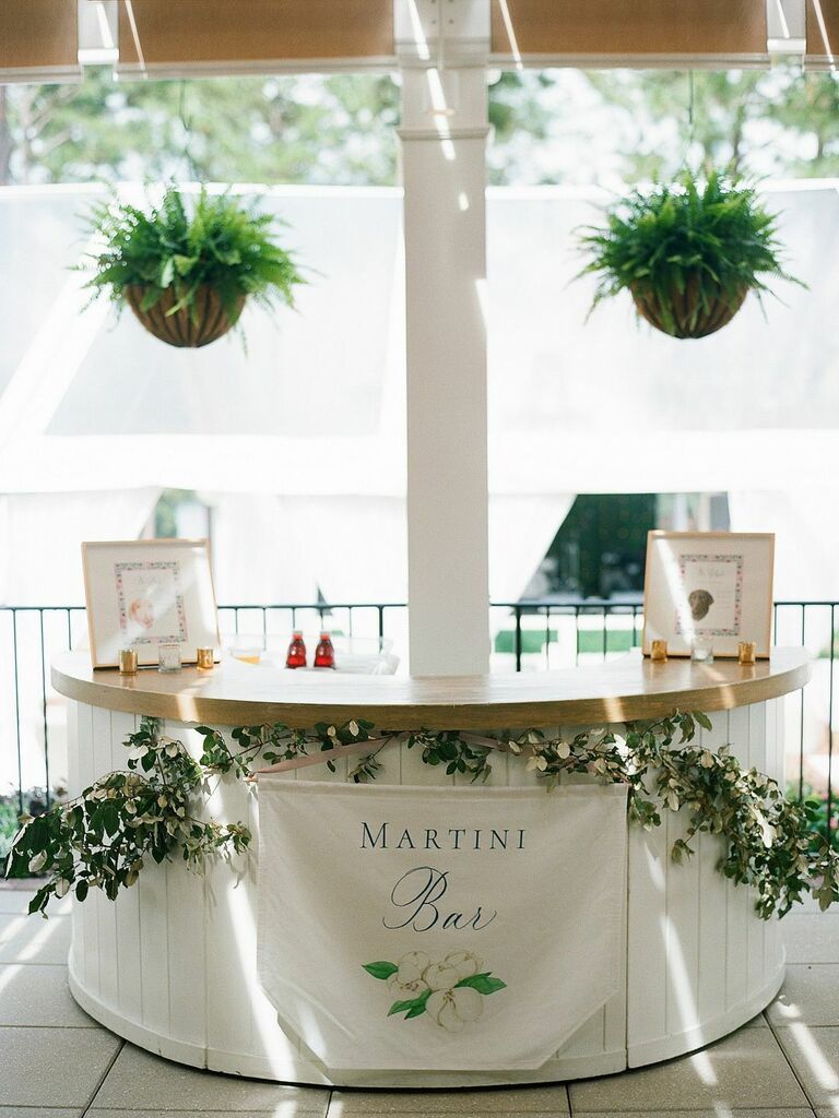 Round wooden martini bar with greenery for outdoor wedding reception