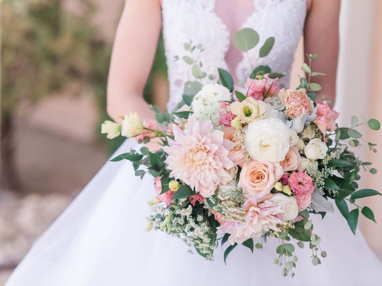 Bride holds a bouquet of pink and white flowers with elegant greenery throughout. 