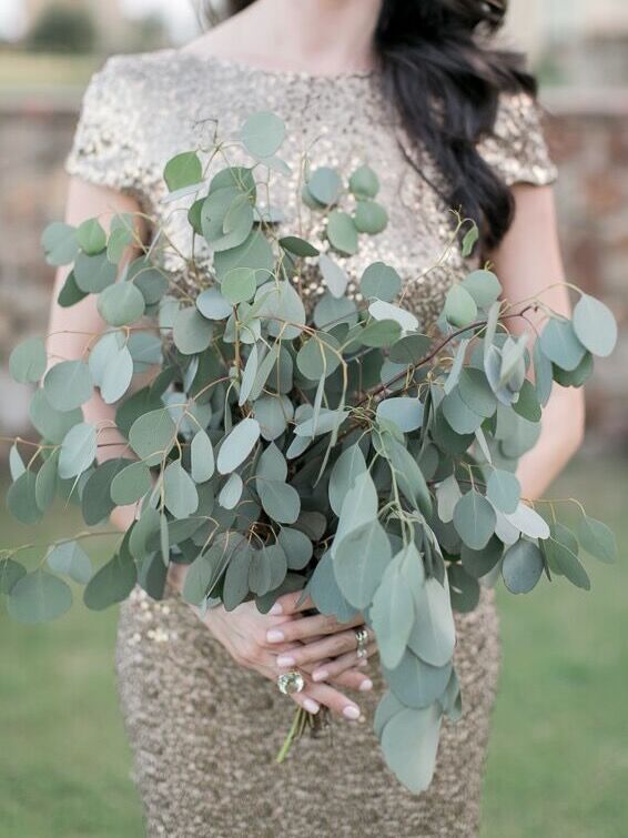 A bridesmaid holds a eucalyptus bouquet.