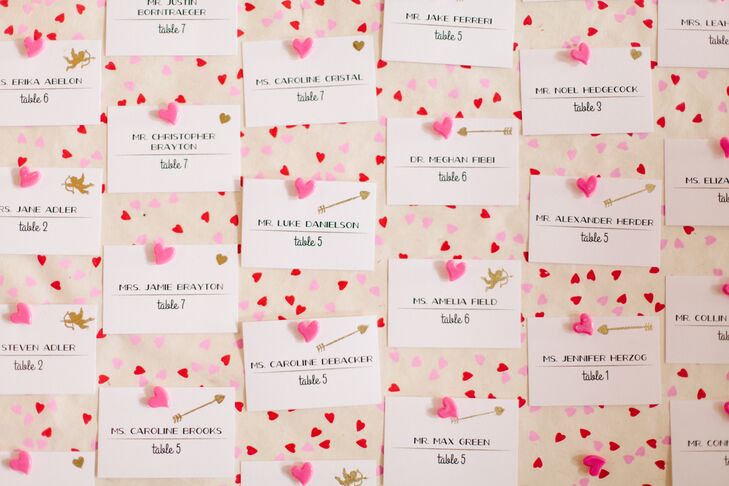 Valentine's Day-themed details included heart-shaped confetti, arrow coasters and a festive red and white escort card display with a sweet arrow motif.