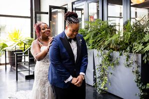 Bride Taps Her Bride on the Shoulder During First Look in Industrial Space With Greenery