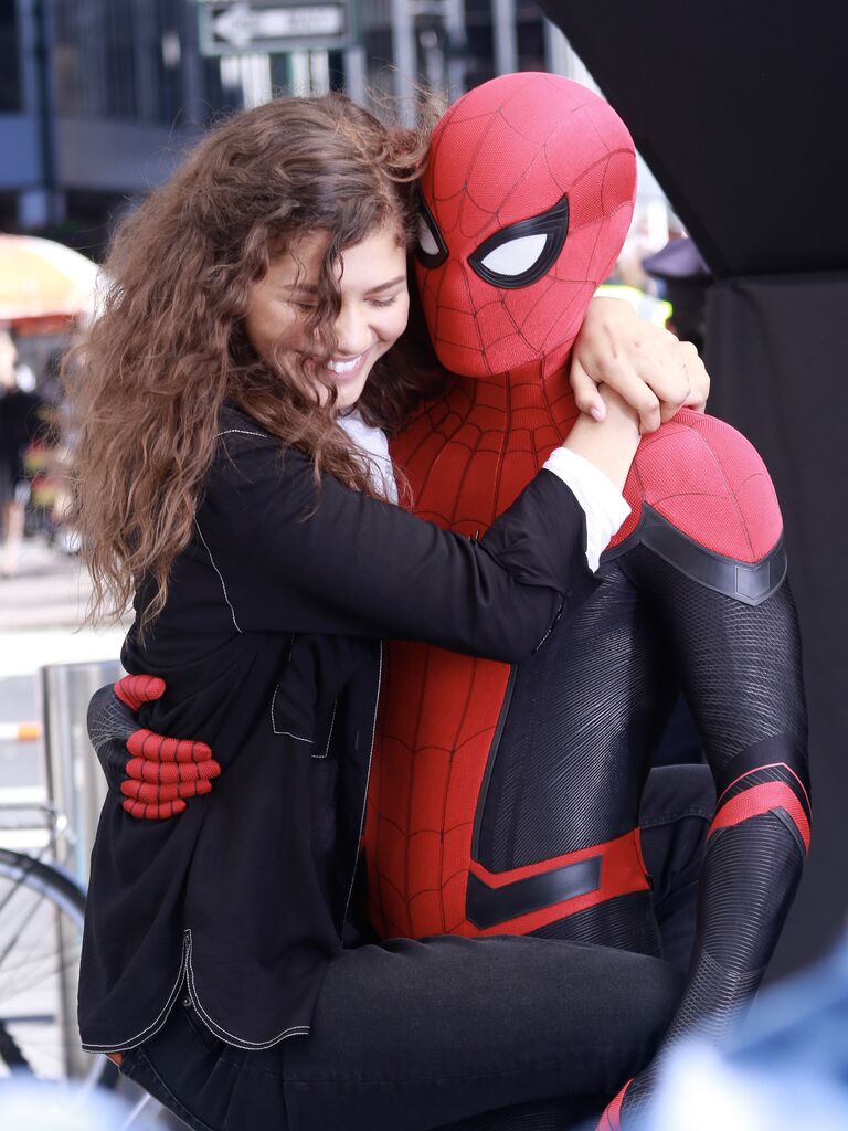 Zendaya hugs Holland who is dressed in a full Spiderman costume. 