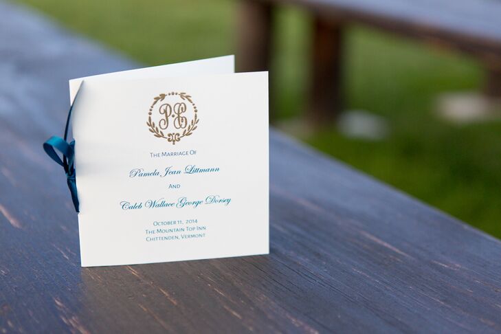 Pam and Caleb hand-embossed their gold custom monogram surrounded by a gold laurel on their stationery, including their folded white ceremony programs. French blue script and a binding ribbon completed the style.