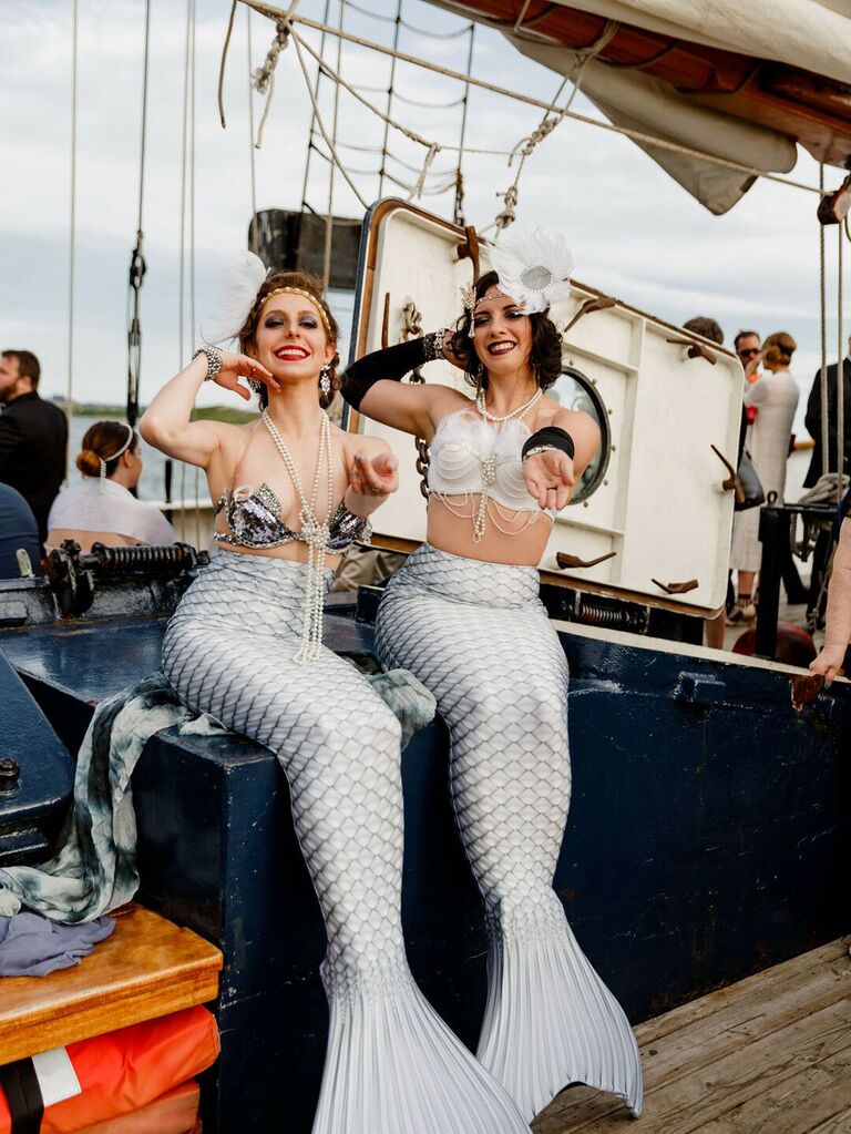 Entertainers dressed as mermaids at nautical summer wedding on boat