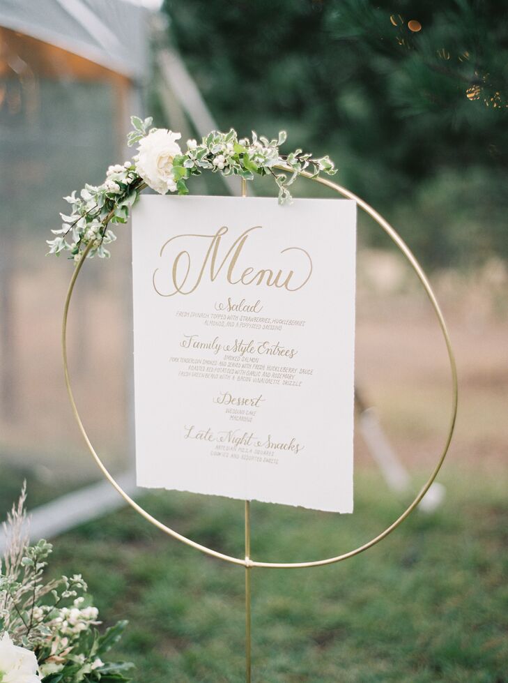 Hanging embroidery hoops, decorated with flowers and greenery, is a creative way to display the menu.