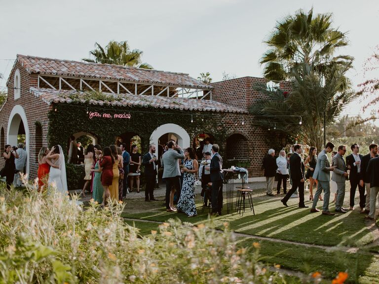 outdoor wedding cocktail hour with guests on lawn in front of stone building