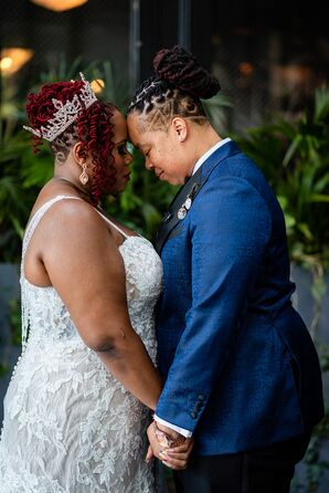 Bride in Dark Blue Suit and Bride in Lace Wedding Dress and Crown, Forehead-to-Forehead