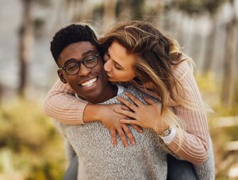how to talk about marriage young couple with man giving piggy back ride to girlfriend kissing him on the cheek