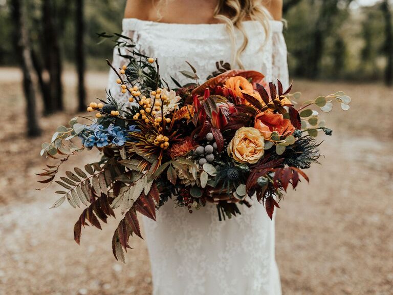 unique fall wedding bouquet with orange roses, greenery and red fall foliage