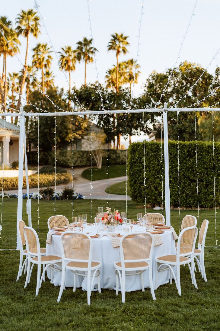 Round Table With Linen Linen on Desert Lawn Under Structure of String Lights