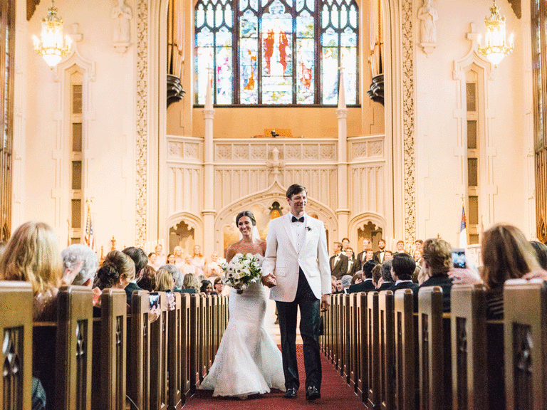 Bride and groom walk down the aisle at a church.
