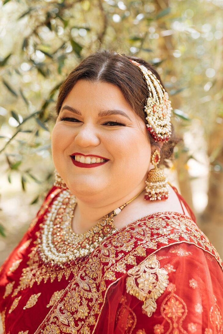 A Bride in a Red Wedding Lehenga and Gold Jewelry Smiles Before Her Ceremony