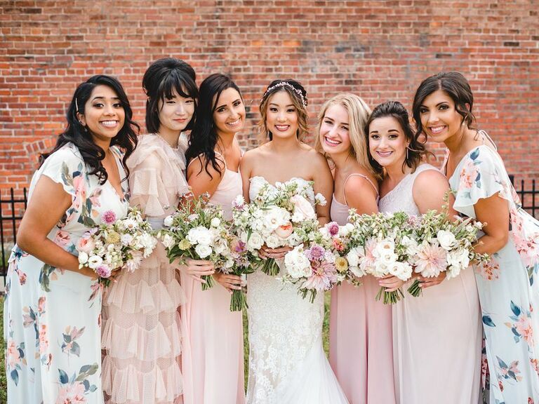 Bridesmaids wear blush pink and light blue floral gowns. 