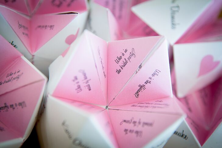 The bride and groom made custom pink and white "cootie catchers" for their ceremony program, full of facts about the groomsmen and bridesmaid. They wanted their guests to become better acquainted with their wedding party during their ceremony.